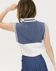 A model wearing an indigo and white intarsia mock neck, sleeveless Fore Sweater.