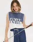 A model wearing an indigo and white intarsia mock neck, sleeveless Fore Sweater.