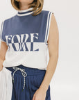 A model wearing an indigo and white intarsia mock neck, sleeveless Fore Sweater.