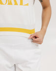 A sleeveless mock-neck sweater with intarsia knit design, featuring horizontal yellow and white stripes and the word 'FORE' printed across the chest.