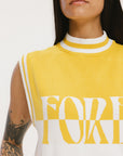 A close-up of a woman wearing a sleeveless sweater with yellow and white colors and the text 'FORE' visible on the front.