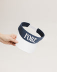 A hand holding a visor with 'FORE' written in bold letters on the front and '04' on the back, against a white background.