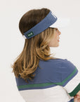A woman wearing a blue and white visor with the brand name 'FORE' on the band, paired with a sporty striped shirt.