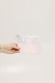 A hand holding a two-toned visor with 'FORE' logo in pink and white colors.