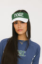 A model wearing a green and white visor with the text 'FORE' across the front.