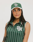A green baseball cap with pinstripe detailing and an embroidered logo worn by a model against a white background.