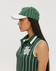 A green baseball cap with pinstripe detailing and an embroidered logo worn by a model against a white background.