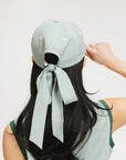 A person viewed from the back wearing a green seersucker hat with a bow