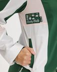 Close-up of a green and pink warm-up jacket with a logo on the sleeve.