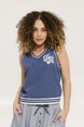A woman wearing a blue sleeveless windbreaker vest with a bold logo on the chest, ribbed armholes, and silicone logos on the upper back.