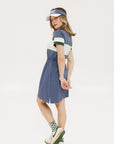 A person wearing a short-sleeved, striped, blue and white dress with a visor and green and white sneakers.