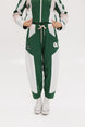 A pair of color-blocked green and white warm-up pants with a pink stripe, featuring a flat drawstring waistband and deep front pockets, branded with the 'Fore All' detail on the back and an FA icon on the inner calf.