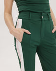 A close-up of a green pant with a white side stripe, focusing on the waist area with a visible belt.