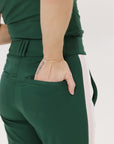 A pair of green Simone Pant with white stripes on the side, front and back pockets, and a zipper fly with snap closure.