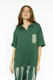 A woman wearing a green button-up shirt with a collar and front pocket, paired with striped pants.