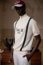 A man wearing a beige zip sweater with vertical green stripes and the text 'Fore All x Khalhon' on the chest.