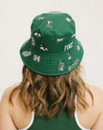 A person wearing a green bucket hat with white embroidered icons.