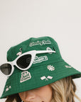 A person wearing a green bucket hat with white embroidered icons.