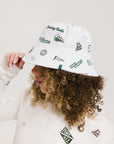 A person wearing a white bucket hat with green embroidered icons.