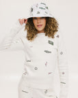 A person wearing a white bucket hat with green embroidered icons.