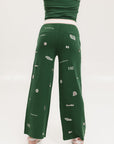 A pair of green Kennedy pants with embroidered icons, paired with a green top and pink shoes.