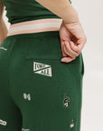 A pair of green Kennedy pants with embroidered icons, paired with a green top and pink shoes.