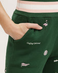 A pair of green Kennedy pants with embroidered icons, paired with a green top and pink shoes.
