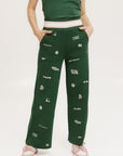 A pair of green Kennedy pants with embroidered icons, paired with a green top and pink shoes.