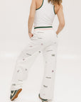 A pair of white Kennedy pants with a checkered print and embroidered icons, displayed on a model.