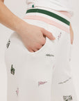 A pair of white Kennedy pants with a checkered print and embroidered icons, displayed on a model.