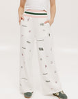 A pair of white Kennedy pants with a checkered print and embroidered icons, displayed on a model.