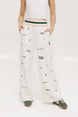 A pair of white Kennedy pants with a checkered print and embroidered icons, displayed on a model.