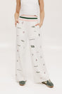 A pair of white Kennedy pants with a checkered print and embroidered icons, displayed on a model.