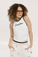 A female model wearing a white sleeveless tank top with a green and pink stripe at the neckline and armholes, and the text 'Chasing Balls' on the chest. She is also wearing white pants with pink and green accents and sunglasses.