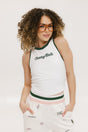 A female model wearing a white sleeveless tank top with a green and pink stripe at the neckline and armholes, and the text 'Chasing Balls' on the chest. She is also wearing white pants with pink and green accents and sunglasses.