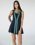 A model wearing a black sleeveless dress with a green vertical stripe detail on the front, designed with a flattering silhouette.