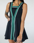 A model wearing a black sleeveless dress with a green vertical stripe detail on the front, designed with a flattering silhouette.