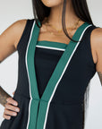 A model wearing a black sleeveless dress with a green vertical stripe detail on the front, designed with a flattering silhouette.