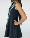 A model wearing a black sleeveless dress with a green vertical stripe detail on the front, designed with a flattering silhouette.