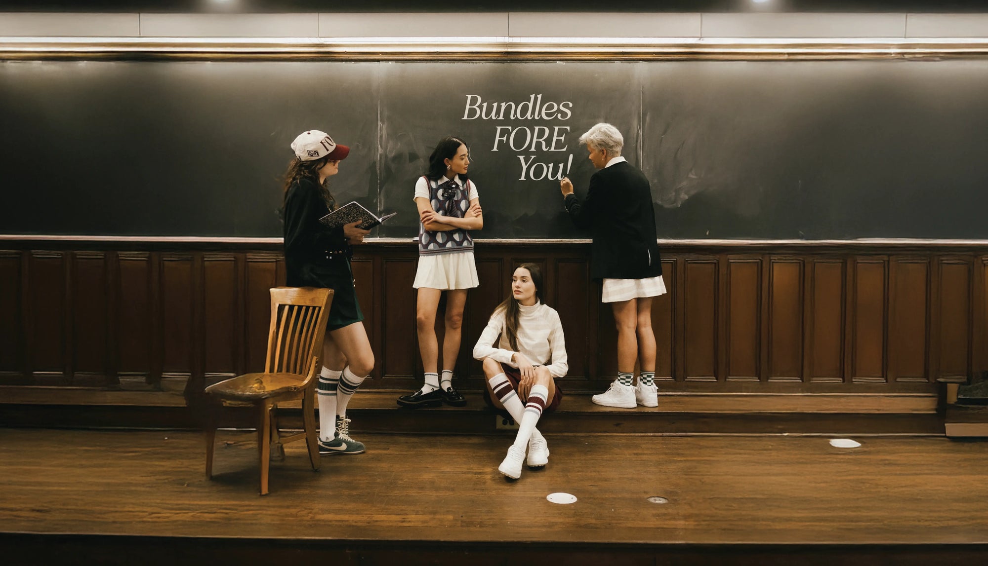 People standing in a subway station with a chalkboard wall displaying 'Bundles FORE You!'.