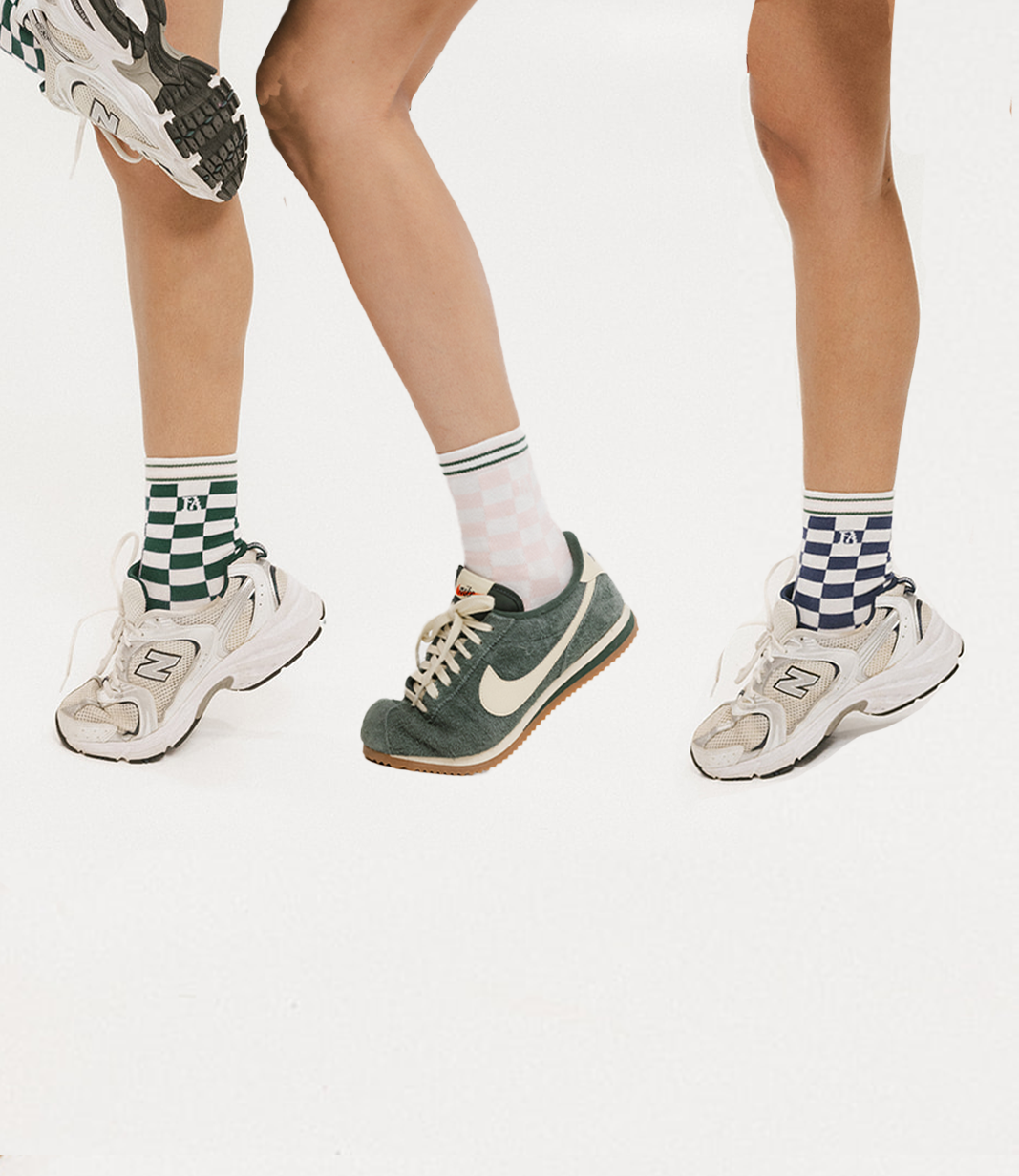 Three pairs of feet wearing different sneakers and socks on a white background