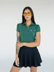 A woman wearing a green polo shirt with a collar, featuring a four-button placket and puff sleeves, paired with a black skirt.